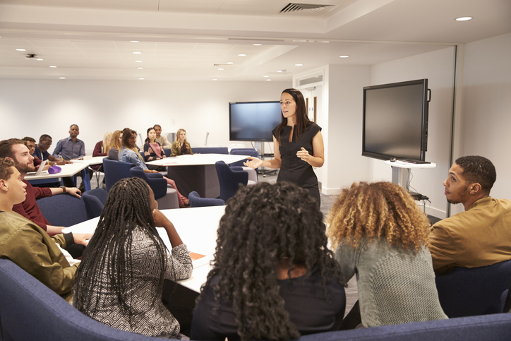 A woman leading a training session with a group of participants.