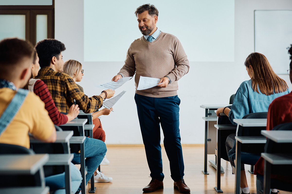 Un professeure remet des devoirs à des étudiants et étudiantes. Un professeure remet des devoirs à des étudiants et étudiantes.
