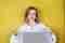 Image d'une étudiante sur un fond jaune avec les deux pouces levés devant un ordinateur portable