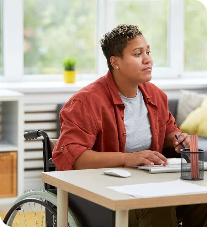 Serious disabled woman concentrating on her work she sitting at her workplace and working on computer.
