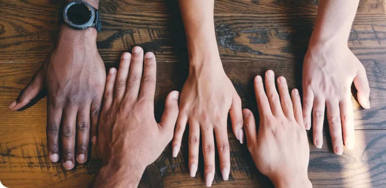 Five hands from different cultures on a brown desk