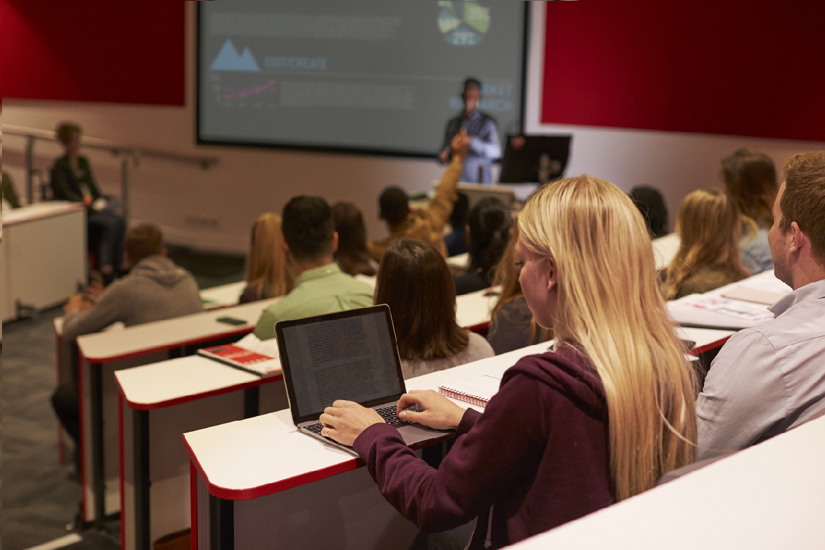 Une étudiante en classe prend des notes sur son ordinateur portable.