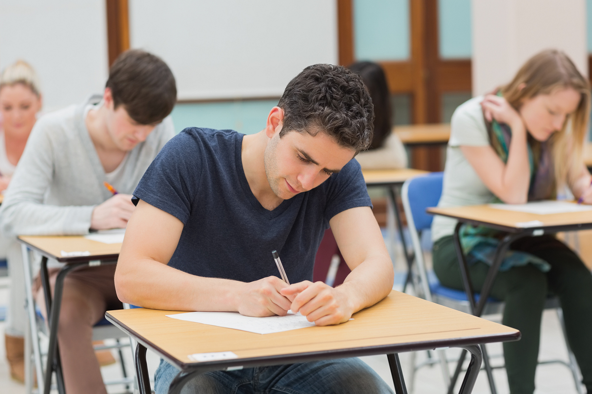 Des étudiants et étudiantes passent un examen dans une salle de classe.